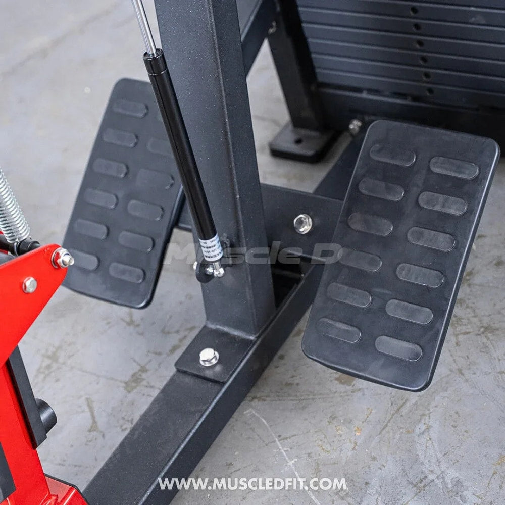 Close-up of seated row gym machine foot pedals on gray floor, strength training equipment